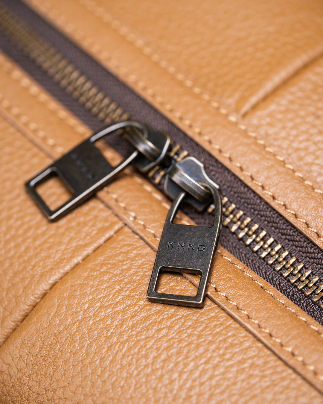 Close up of brass zippers of tan leather KNKG HERITAGE Backpack