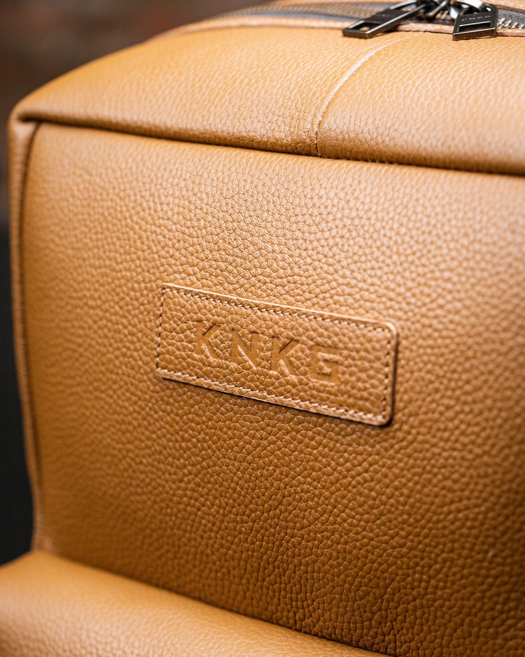 Close up of leather patina logo on tan KNKG HERITAGE Backpack