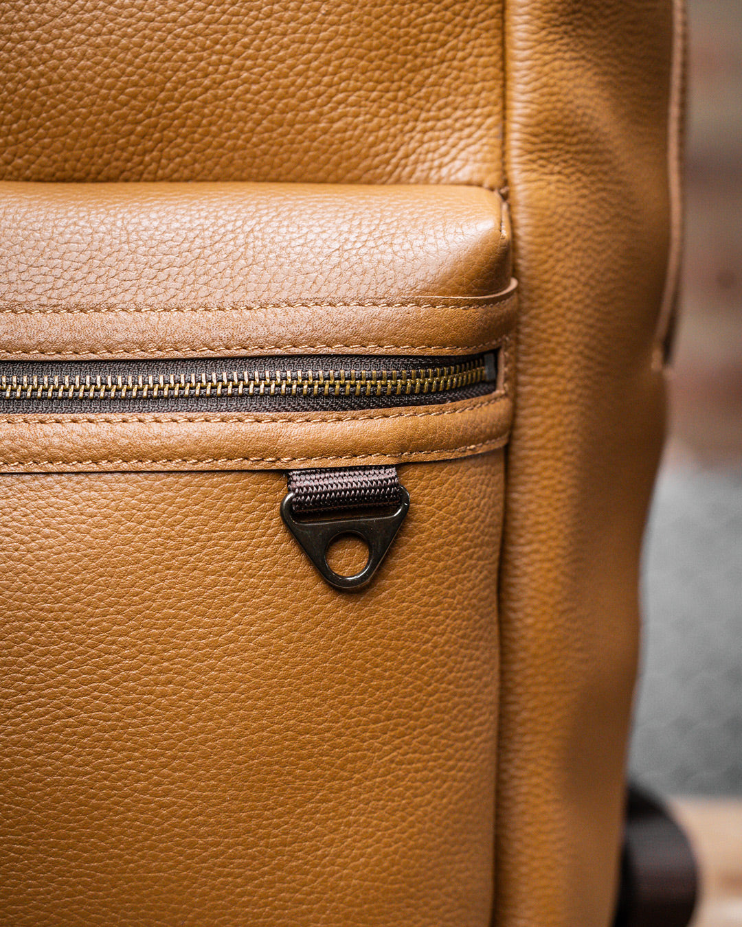 Close up of brass buckles and zippers of tan leather KNKG HERITAGE Backpack