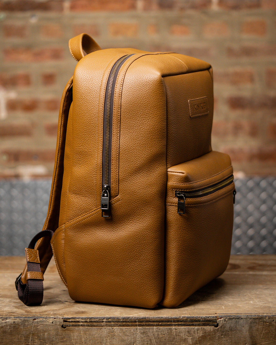 Side view of tan leather KNKG HERITAGE Backpack