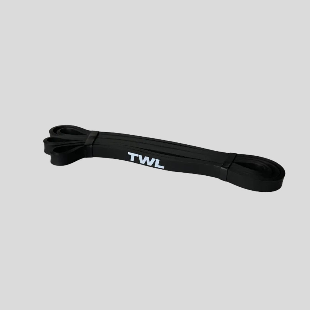 A black resistance band loop with white 'TWL' branding, lying on a light gray surface.