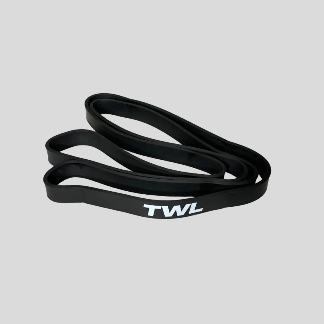 A black silicone resistance band with the white text 'TWL' printed vertically on it, resting on a light gray surface.