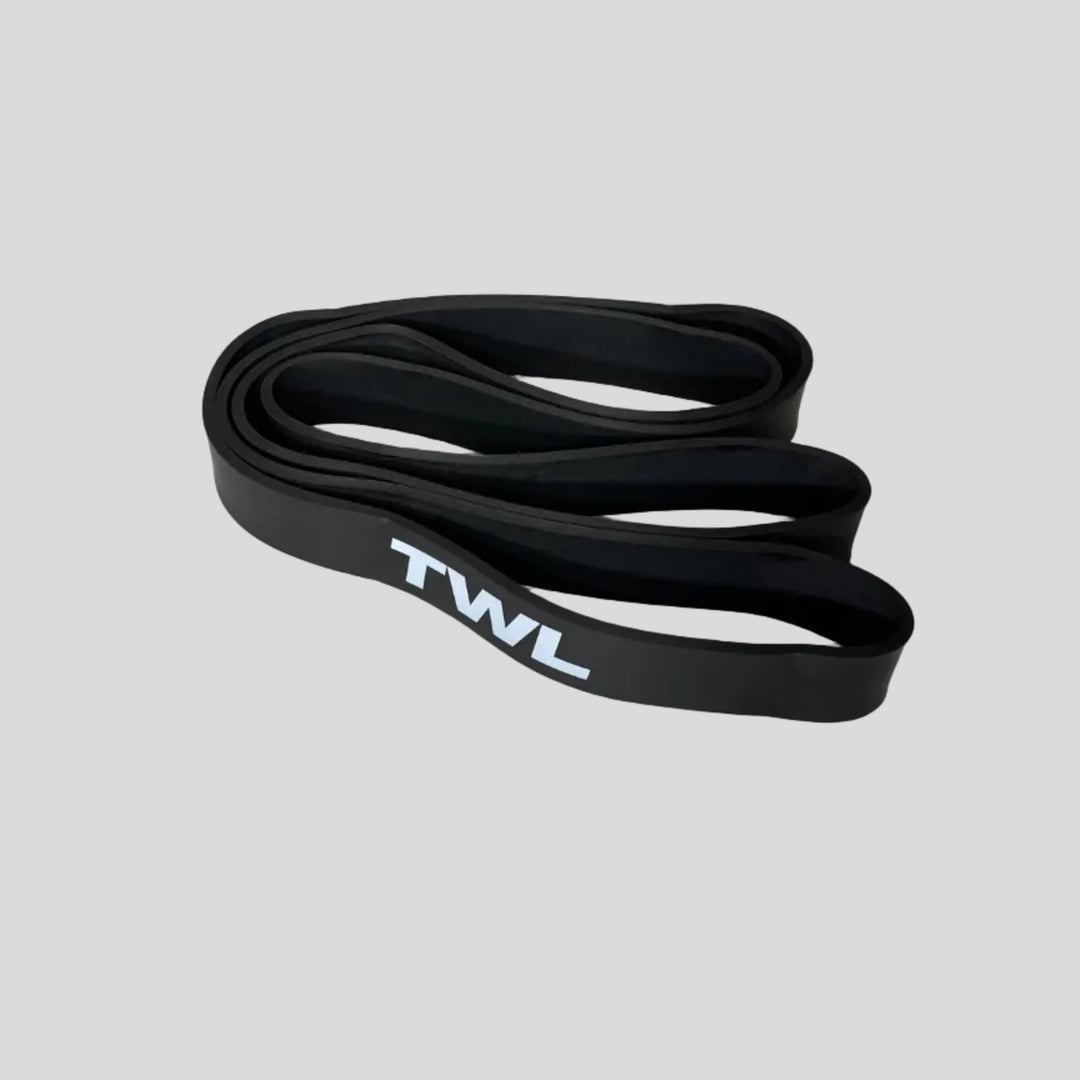 A black silicone resistance band with a white 'TWL' logo printed on the side, coiled on a light gray surface.
