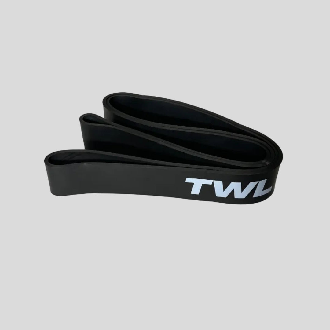 A black silicone resistance band with the white text 'TWL' printed on it, shown on a light gray surface.