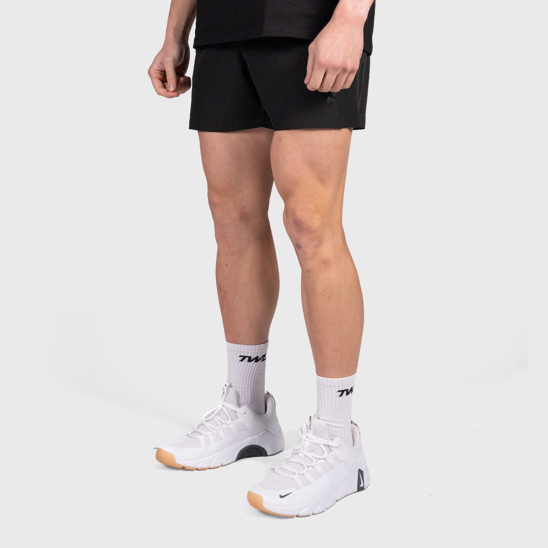 Man wearing the TWL Men's Rep Shorts 5" in Blackout, full-length front view showing the fit