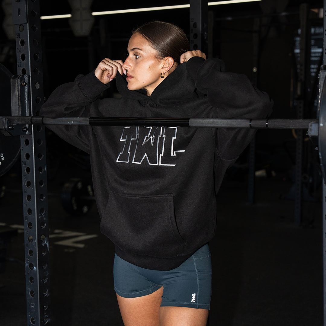 TWL Ascend Hoodie black – oversized fleece hoodie - in gym on female model doing squats